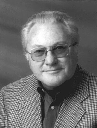 Black and white portrait of a person wearing a checkered jacket and a dark shirt.