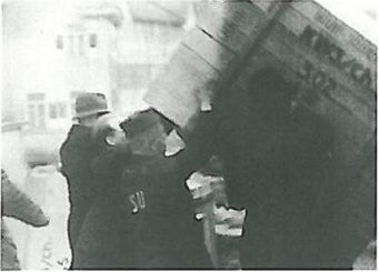 Beim Verladen der Umzugskisten. Foto: MPG Archiv Berlin-Dahlem In einer historischen Schwarz-Weiß-Aufnahme heben zwei uniformierte Männer eine große Kiste oder einen Behälter, vermutlich bei einer Arbeitssituation im Freien.