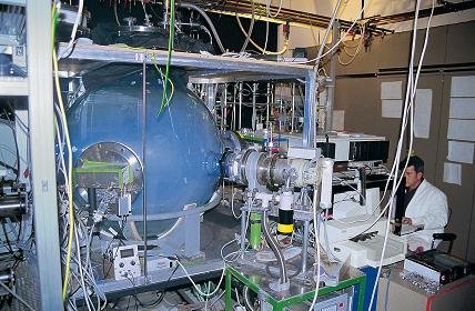 Das alte Ozonlabor mit Glaskugel am MPI für Chemie. Bild: MPI für Chemie Komplexe Laborapparatur mit großem blauen Reaktionsbehälter, verbundenen Rohren und einem Forscher im weißen Kittel.