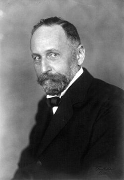 Black and white portrait showing a man in a dark suit and bow tie.
