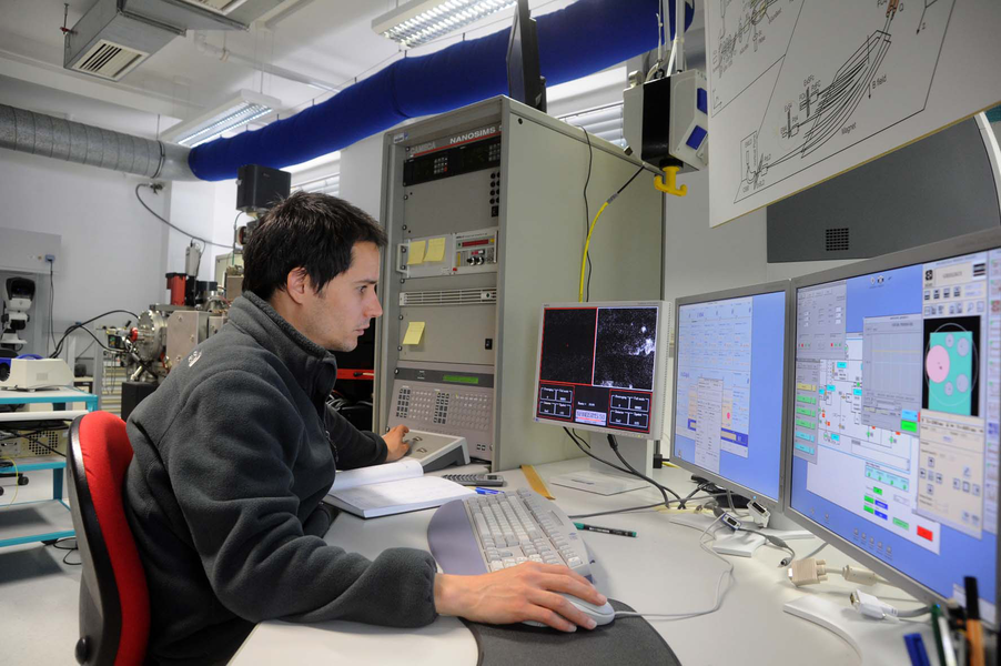 Person arbeitet an einem Computer mit mehreren Monitoren in einem technischen Labor.