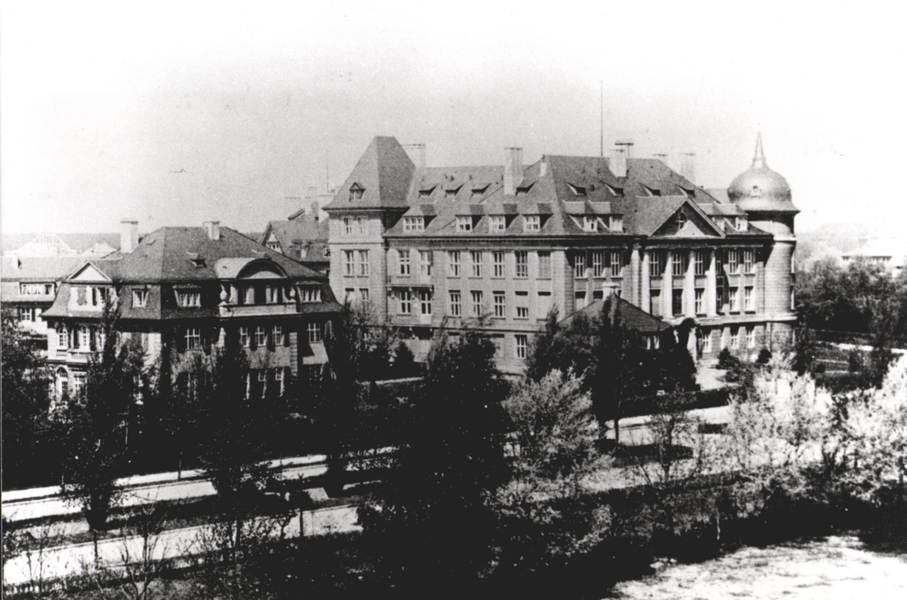 Historic large building complex with multiple floors and a distinctive rounded tower.