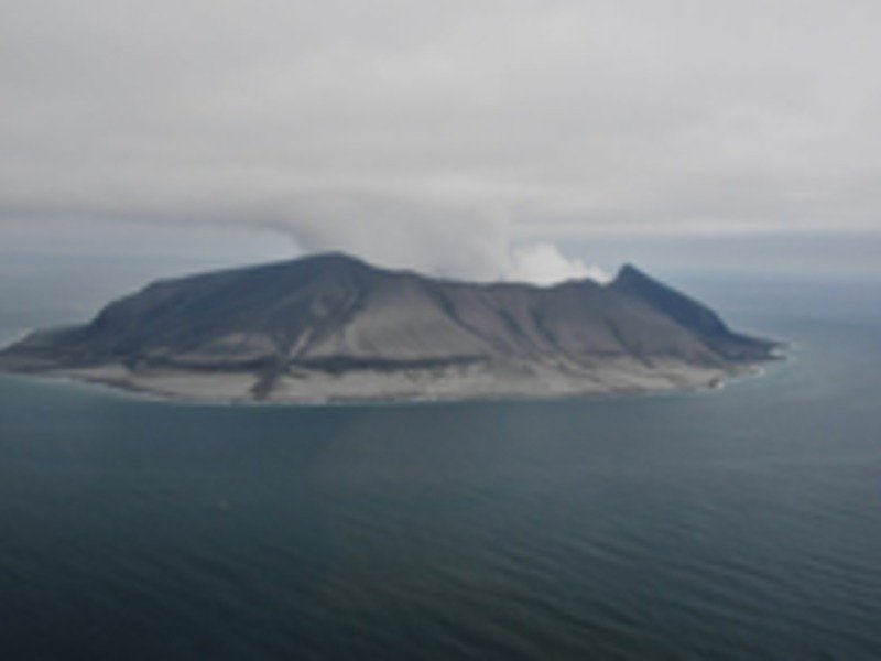 Blick auf die Südostseite des Kasatochi nach dem Ausbruch vom 7.8.2008. Das Kliff in der Flanke markiert die ehemalige Küstenlinie. Die ehemals grüne Insel ist von Staub und Asche bedeckt. Derselbe Staub, den auch die CARIBIC-Wissenschaftler in der Luft über Europa gemessen haben.