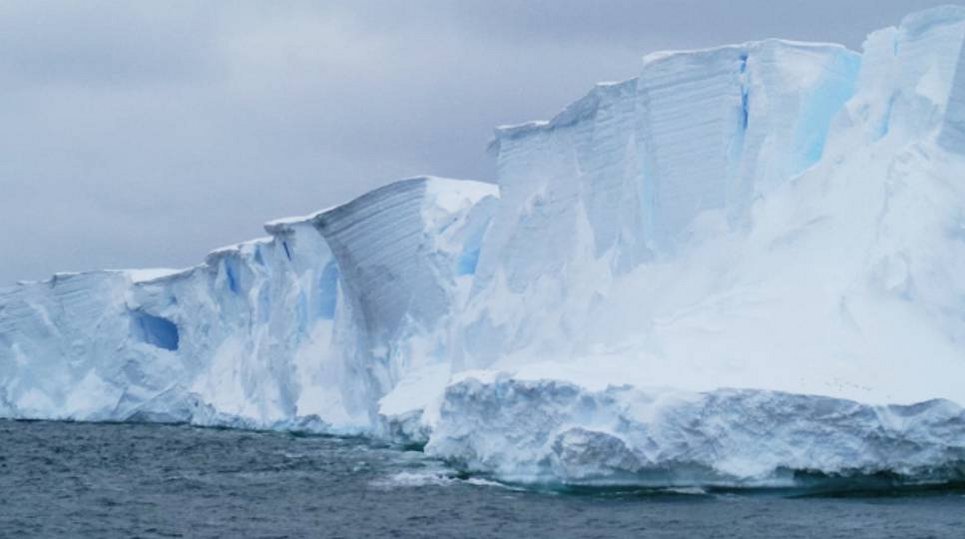 White icebergs with jagged surfaces tower over dark waters, set against a grey, overcast sky.
