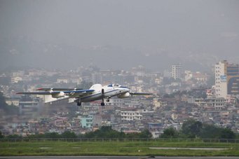 Airplane taking off in front of a backdrop of a cityscape.