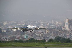 Abhebendes Flugzeug vor einer Häuserkulisse.