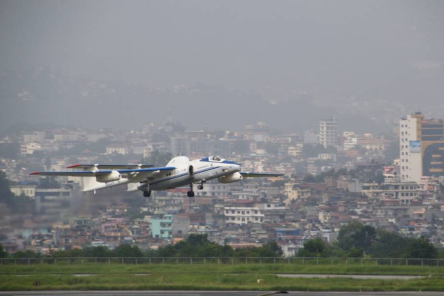 Abhebendes Flugzeug vor einer Häuserkulisse.