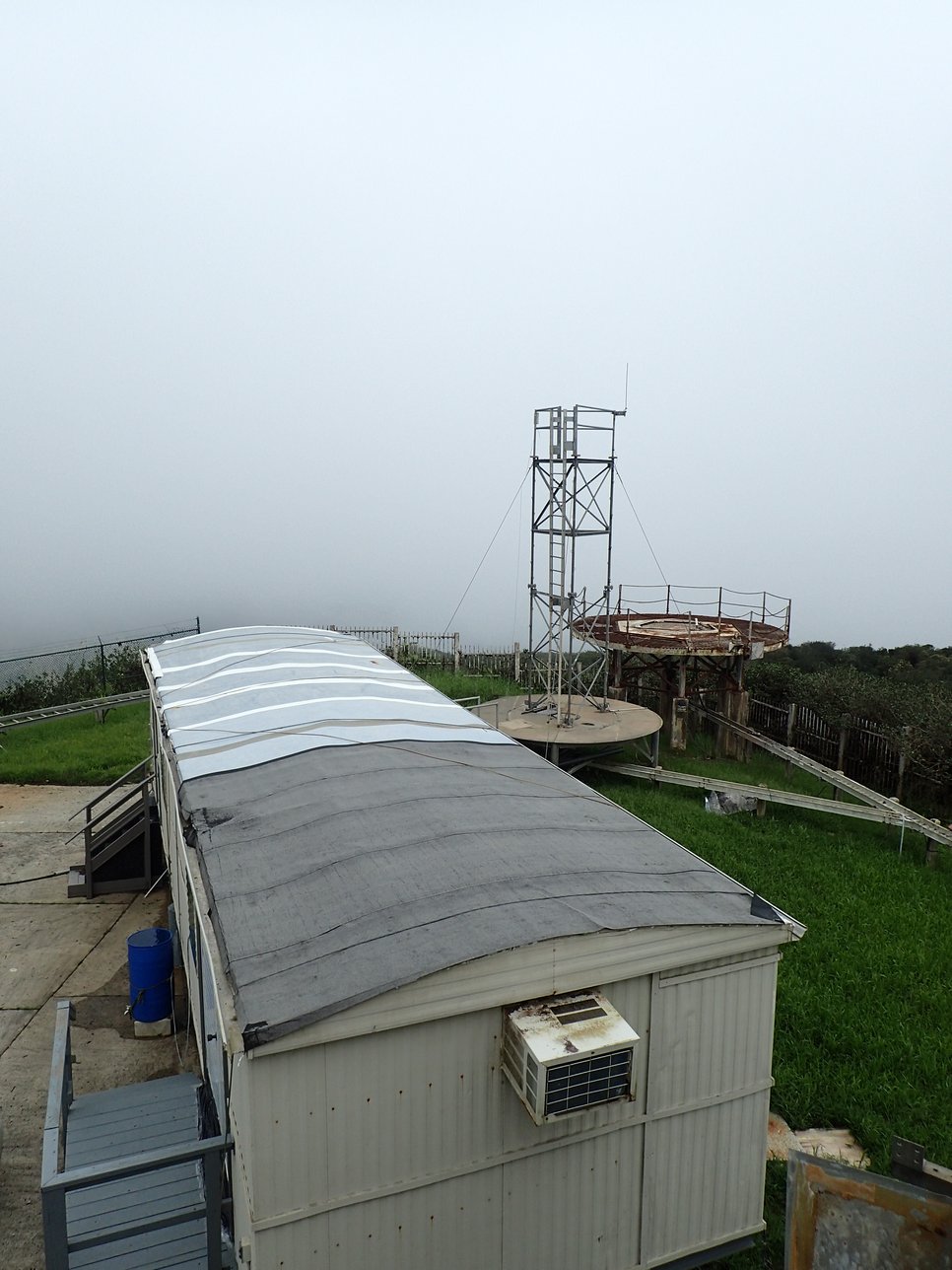 Metal tower and rectangular building with air conditioner in foggy landscape.