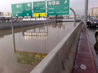 Researchers found that two larger-scale meteorological phenomena were associated with extreme rainfall events in the Middle East, including the 2009 Jeddah flood pictured here. Urban highway scene with significant flooding, causing road signs for Al Ruwalis, Madinah, and Al Balad to be partially submerged, with vehicles parked on the side.