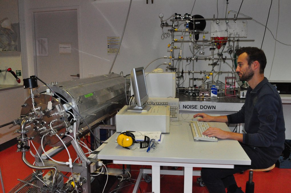 Person works between measuremnt instrument on a computer.