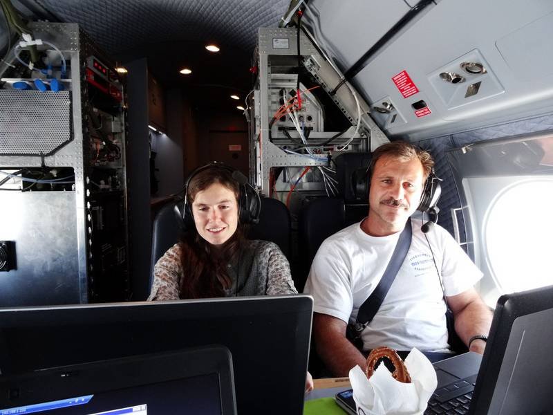 Mira Pöhlker (on the left) and Tommy Leder (on the right) with headsets seated in an aircraft cockpit, surrounded by technical equipment.