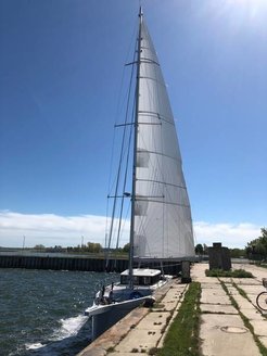 Die Forschungsyacht Eugen Seibold neben einem Pier auf sonnigem Gewässer unter blauem Himmel.