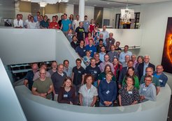 Große Gruppe von Menschen versammelt auf einer modernen, weißen Treppe in einem Gebäude.