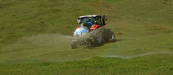 Eine wichtige Quelle für Feinstaub: Landwirtschaftliche Ammoniakemissionen aus Düngung und Viehzucht. Quelle: Wald1siedel/Creative-Commons Lizenz Traktor mit Tankaufsatz versprüht Flüssigkeit auf grasbedecktem Hügel.