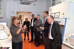 Group observing lab equipment; detailed explanation by a presenter.
