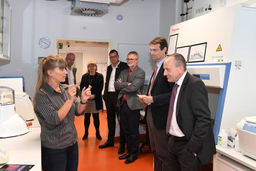 Group observing lab equipment; detailed explanation by a presenter.