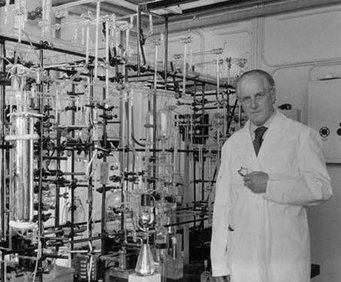 Friedrich Paneth besides a mass spectrometer, circa 1956. Source: MPI for Chemistry Scientific laboratory featuring extensive glass apparatus and a researcher wearing a lab coat.