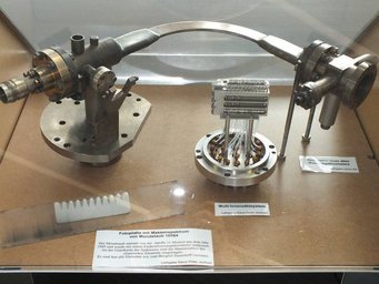 Deflection tube of an old mass spectrometer; front left: Photo plate with mass spectrum of lunar dust 10084. Photo: S. Benner Historical mass spectrometer parts including a multi-ion counting system and a photographic plate with moon dust mass spectrum.