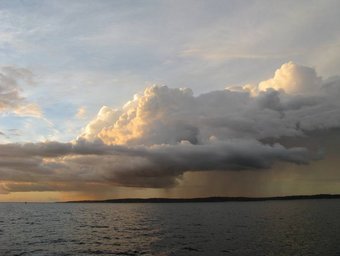 Rain clouds over the sea in Brazil. Source: Christopher Pöhlker Dark storm clouds over a body of water with distant land visible.