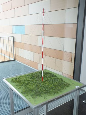 Model of the research tower ATTO, which stands north of Manaus in the Brazilian rainforest. Photo: S. Benner Detailed scale model of a red and white research tower with supporting cables on a green terrain base.