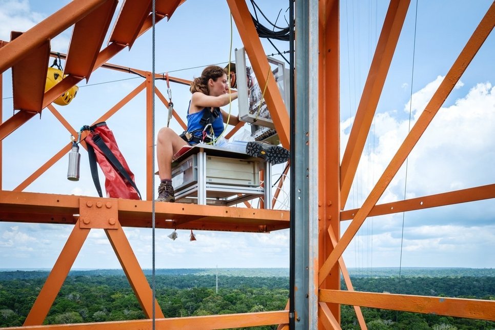 Researcher Nora Zannoni sits on a high scaffold on the ATTO research tower, operating technical equipment high above the Brazilian rainforest.