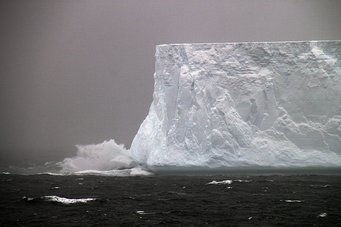 Iceberg in Antarctica: Temperature in the Southern Ocean was more tightly linked to the extent of the Antarctic glaciation during past greenhouse climates than previously thought. Source: Alfred Wegener Institute, Thomas Ronge CC-BY 4.0 Massive iceberg with jagged edges amidst stormy seas and crashing waves.