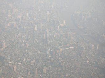 Multiphase buffering effect of emitted ammonia controls aerosol pH, thereby influencing the haze chemistry and formation of aerosol particles, especially nitrate, sulfate and ammonium. It shows a close link between the nitrogen cycle and atmospheric chemistry. The picture shows a hazy day in Guangzhou, China. Source: Ulrich Pöschl,  MPI for Chemistry Aerial view of a city in thick smog, with many high-rise buildings and a river visible.