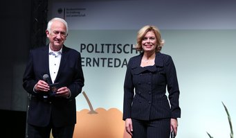 Landwirtschaftsministerin Julia Klöckner ehrt Feuerökologen Johann Goldammer. Johann Goldammer und Julia Klöckner stehen auf einer Bühne, Hintergrund zeigt das Logo des Bundesministeriums für Ernährung und Landwirtschaft.