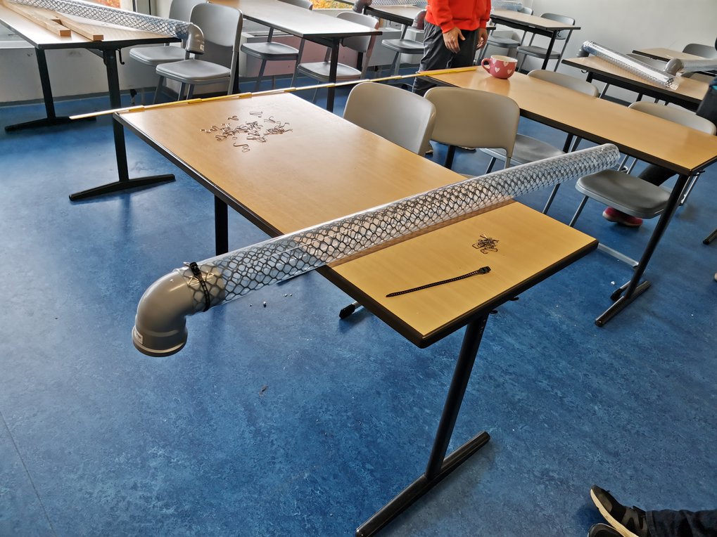 PVC-Rohr mit Drahtgeflecht auf einem Tisch in einem Klassenzimmer.