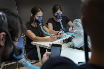 Studienteilnehmer in einer speziell isolierten Kammer an der Technischen Universität von Dänemark, wo die Experimente stattfanden. Gelegentlich mussten sie mit einer speziellen Maske atmen, die es ermöglicht, die chemische Zusammensetzung von Atem und Haut getrennt zu messen. Studienteilnehmer:innen in einer speziell isolierten Kammer an der Technischen Universität von Dänemark, wo die Experimente stattfanden. Sie tragen Masken(blau) mit Schläuchen.