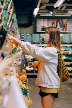 Junge Frau beim Einkaufen im Supermarkt, mit Maske