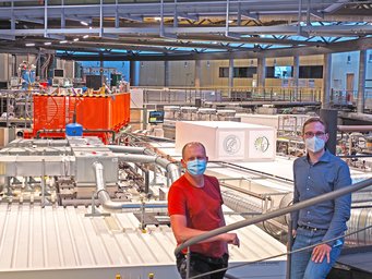 Christopher Pöhlker (l.) und Jan-David Förster nutzen für ihre Forschung auch das Röntgenmikroskop MAXYMUS (im Hintergrund zusehen) im Helmholtz-Zentrum Berlin. Christopher Pöhlker (l.), mit Maske, und Jan-David Förster (r), mit Maske. IN Hintergrund: Das Röntgenmikroskop MAXYMUS.