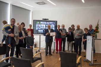 Bei der halb digitalen, halb präsenten Verleihung des Honorary Fellowship der IAG. Dr. Klaus Peter Jochum (Mitte) im Kreis von Kolleg:innen bei der hybrid stattfindenden Preisverleihung. Im Hintergrund: Smartboard.