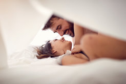 Man and Woman in bed smiling at each other lovingly