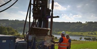 Bohrgerät in Aktion: Im Rahmen des ELSA-Projekts werden Sedimentbohrkerne in einem Trockenmaar bei Schalkenmehren gewonnen. Bohrgerät auf einem grünen Feld mit zwei Arbeitern im Vordergrund.
