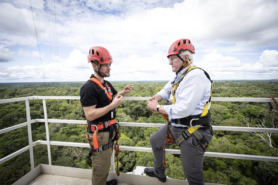 Two people in safety gear stand on a platform overlooking a forest canopy. German President Frank-Walter Steinmeier (r.) with Stefan Wolff, representative of the ATTO project from the Max Planck Institute, on a platform of the Amazon Tall Tower Observatory (ATTO).