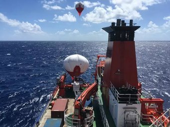 Vom Forschungsschiff Maria S. Merian starteten Max-Planck-Forschende 2020 in der Karibik Cloudkites – Ballone, mit denen sie die Mikroprozesse in tropischen Wolken untersuchen. Das Projekt Eurec4a soll den Einfluss der Erderwärmung auf die Wolken- und Niederschlagsbildung in den Tropen klären – eine wichtige, bislang aber nicht komplett verstandene Rückkopplung im Klimawandel. Ein rotes Forschungsschiff auf dem Ozean, im Hintergrund schwebt ein Ballon.