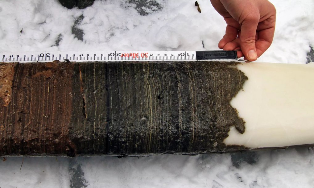 Bohrkern mit verschiedenen Sedimentschichten, gemessen im Schnee.