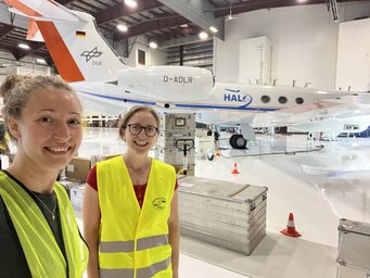 Linda Ort (Max-Planck-Institut für Chemie) und Kollegin Franziska Weyland (Johannes-Gutenberg-Universität Mainz) im Hangar. Linda Ort (l., Max-Planck-Institut für Chemie) und Kollegin Franziska Weyland (Johannes-Gutenberg-Universität Mainz) im Hangar vor dem Forschungsflugzeug HALO.