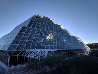 Outside view of the experimental rainforest at Biosphere 2 in Oracle, Arizona. Geometric glass building with angular design under a clear sky. Outside view of the experimental rainforest at Biosphere 2 in Oracle, Arizona.