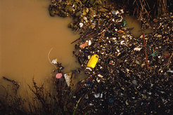 Wasser- und Bodenverschmutzung gefährden zunehmend die menschliche Gesundheit. Im Bild: Müll, der in braunem Wasser treibt