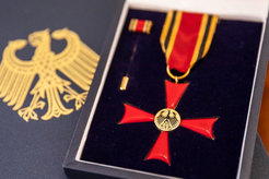 Abbildung des Bundesverdienstkreuzes am Bande. Das Verdienstkreuz am Bande des Verdienstordens der Bundesrepublik Deutschland wird in wenigen Fällen persönlich durch den Bundespräsidenten überreicht, etwa aus Anlass des Tages der Deutschen Einheit.
