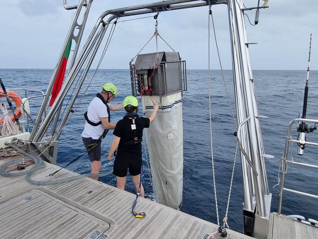 Zwei Personen auf einem Boot installieren wissenschaftliches Gerät über dem Meer.