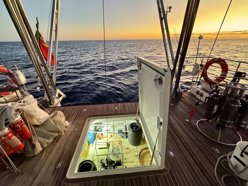 Schiffdeck mit offenem Laderaum, Blick auf das Meer bei Sonnenuntergang.