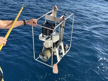 Wissenschaftliches Messgerät wird über das Meer gehoben.