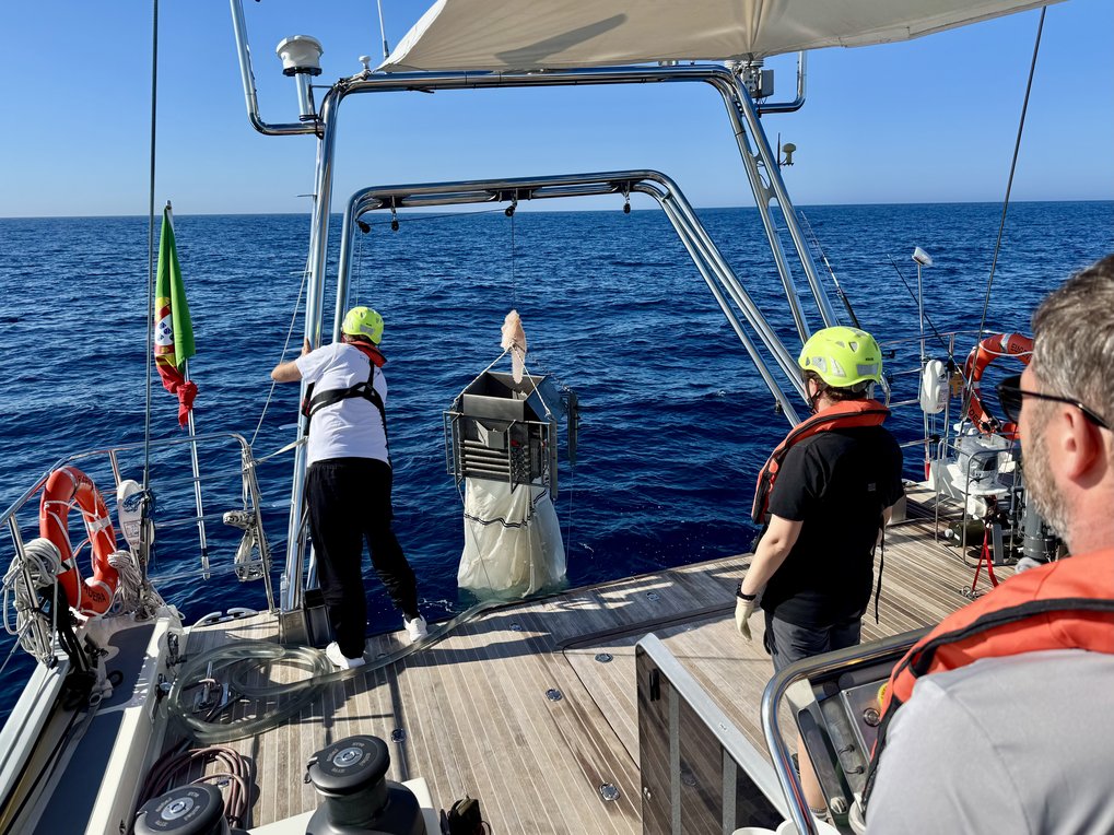 Researchers on a boat deploying oceanographic equipment into the sea.